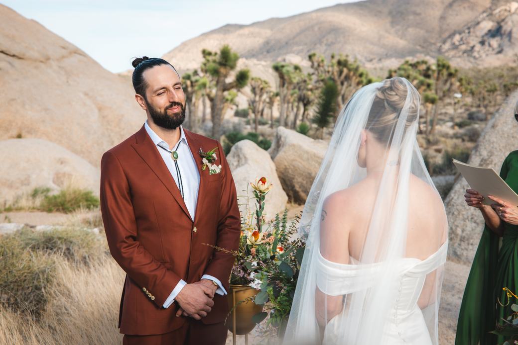 Groom watching his bride during a desert wedding ceremony