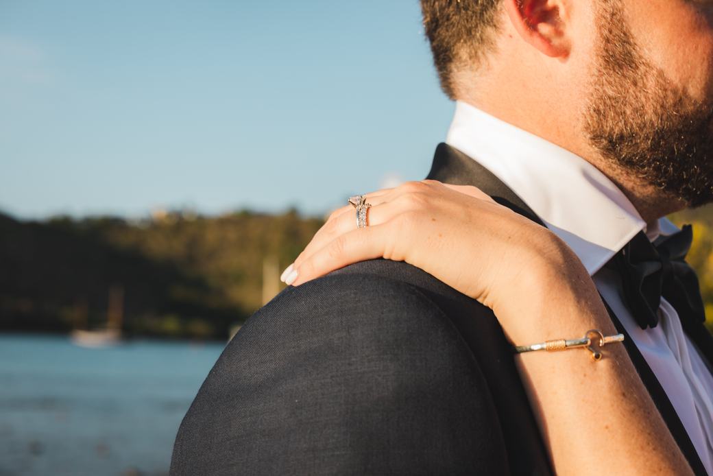 Bride’s hand on the groom’s shoulder at sunset