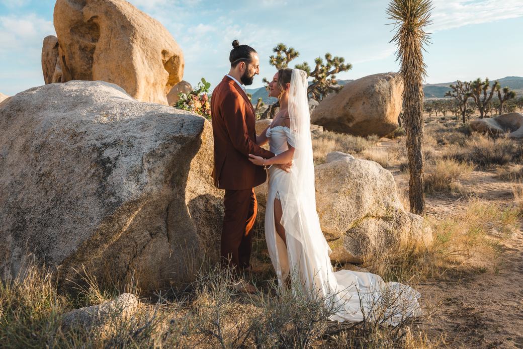 Newlyweds walking together among desert boulders